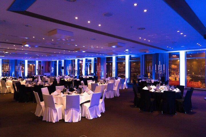 Eleganter Bankettsaal im ATLANTIC Hotel Kiel, festlich gedeckte Tische, stimmungsvolle blaue Beleuchtung.