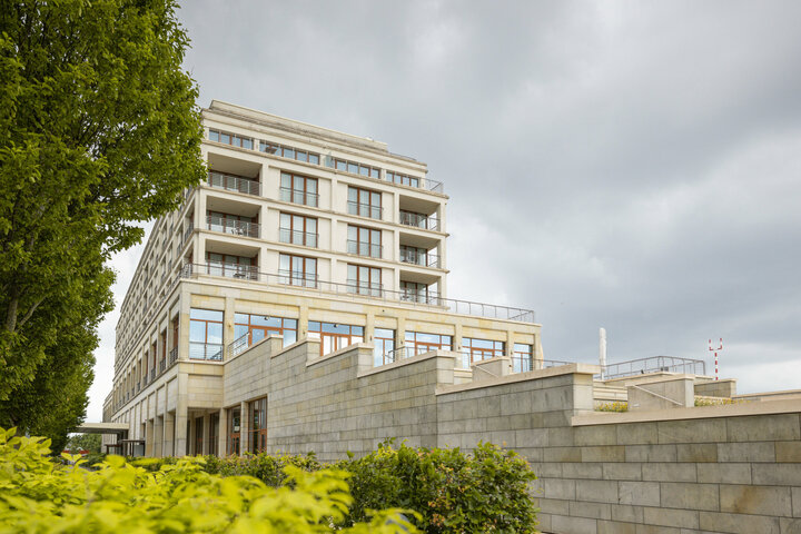 Die Außenansicht der Restaurantterrasse mit viel Grün vor bewölktem Himmel