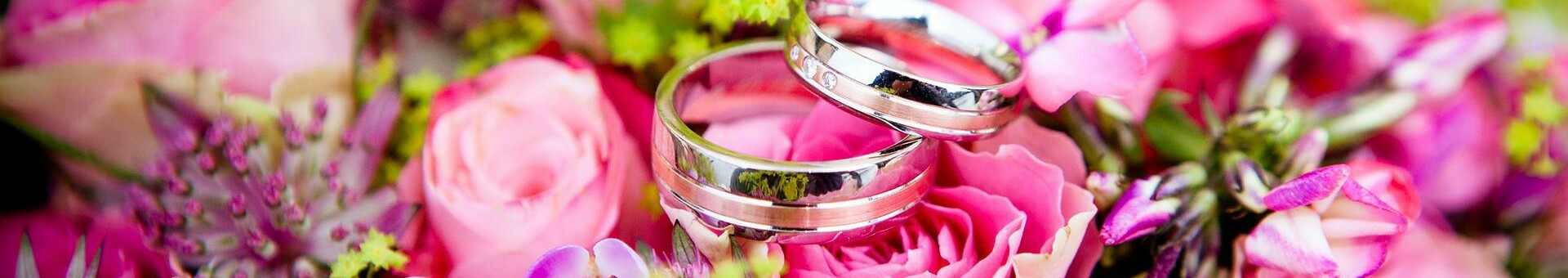 Flower decoration for a wedding shoot Two silver wedding rings on a bouquet of pink roses and colorful flowers.