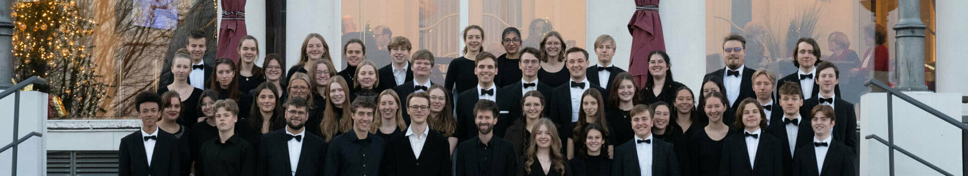 Eine große Gruppe festlich gekleideter Menschen steht vor dem ATLANTIC Grand Hotel Travemünde.