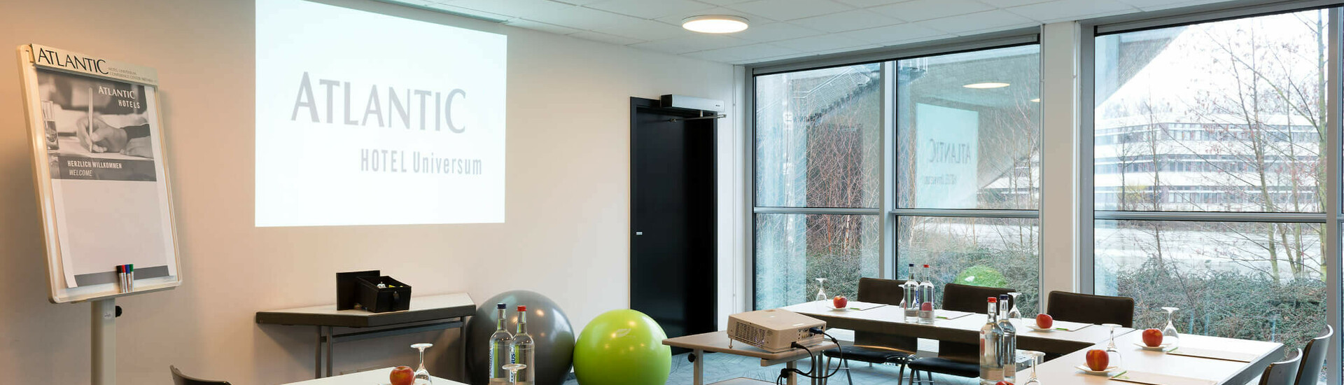 ATLANTIC Hotel Universum – Conference Room 2 Bright conference room in the ATLANTIC Hotel Universum with tables, chairs, projector and flipchart, view to the outside.