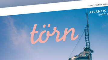 Magazine title "törn" in front of blue sky, showing modern building and logo of Atlantic Hotels.