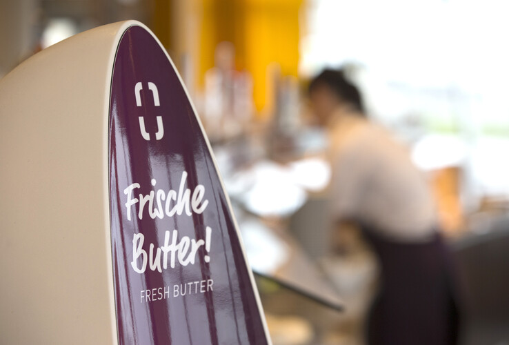 Sign with "Fresh butter" in the ATLANTIC Hotel Sail City, blurred background with person in the restaurant.