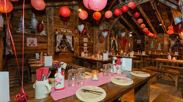 Gemütliche, rustikale Stube im ATLANTIC Grand Hotel Bremen mit Holztischen, rot-weißer Deko und warmem Licht.