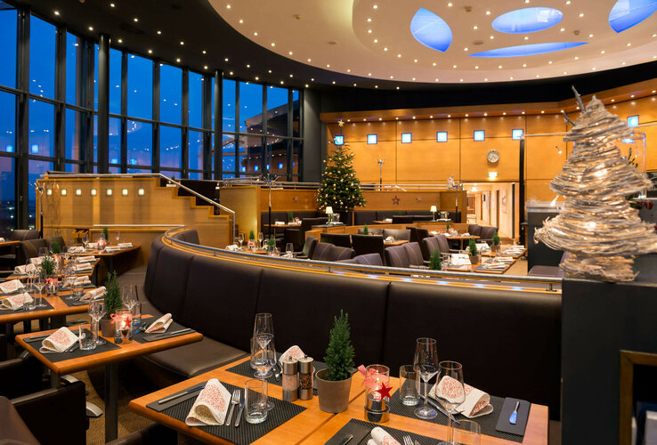 Modernes Restaurant im ATLANTIC Hotel Airport Bremen, festlich gedeckte Tische, hohe Fenster, weihnachtliche Dekoration.