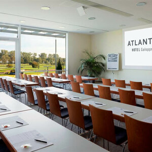 Heller Konferenzraum im ATLANTIC Hotel mit Reihen von Tischen, Stühlen und Blick auf grüne Wiesen.