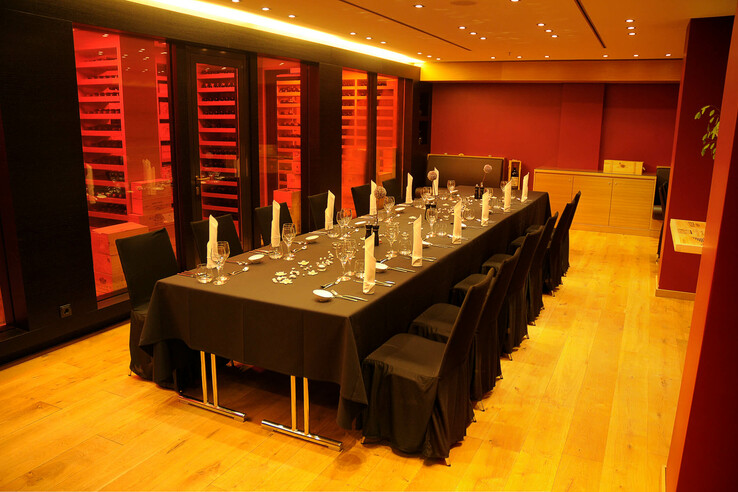 Elegant dining room in the ATLANTIC Hotel Kiel with a long, laid table and atmospheric lighting.