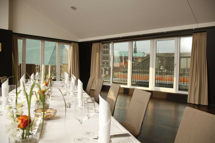 Eleganter Konferenzraum mit gedecktem Tisch und Panoramablick auf Lübecks Dächer.