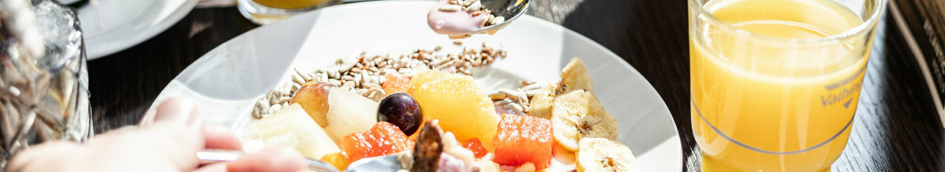 Auf einem gedeckten Frühstückstisch steht ein Birchermüsli und zwei Gläserorangensaft