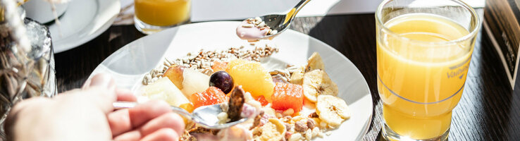 Auf einem gedeckten Frühstückstisch steht ein Birchermüsli und zwei Gläserorangensaft