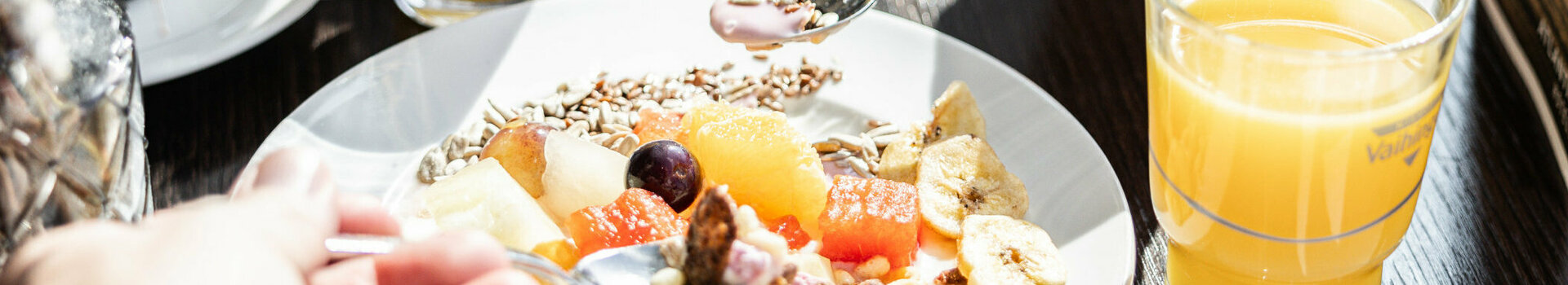 Auf einem gedeckten Frühstückstisch steht ein Birchermüsli und zwei Gläserorangensaft