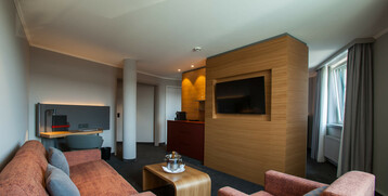 Modernes Hotelzimmer mit gemütlicher Sitzecke, Flachbild-TV und Schreibtisch im ATLANTIC Hotel Airport Bremen.
