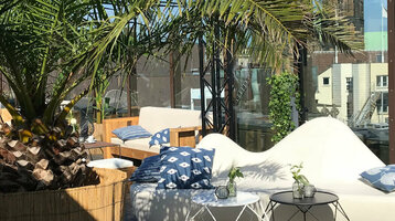 Dachterrasse des ATLANTIC Grand Hotel Bremen mit Palmen, Sitzgelegenheiten und Blick auf Bremer Domtürme.