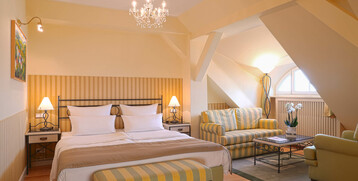 Gemütliches Hotelzimmer mit Doppelbett, Sitzecke, Kronleuchter und Dachfenster im ATLANTIC Grand Hotel Travemünde.