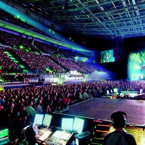 ÖVB Arena während einer Veranstaltung Große, gut besuchte Konzertarena mit Bühne, bunten Lichtern und Tonmischpult im Vordergrund.