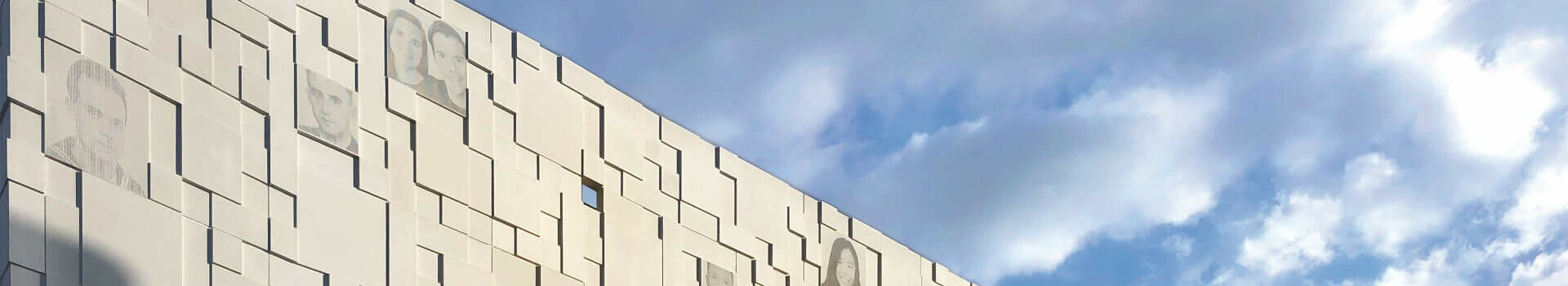 Fassade des ATLANTIC Hotel Sail City, Bremerhaven, mit geometrischen Mustern und Himmel im Hintergrund.