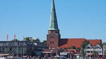 View from the sea over the Travemünde church and the promenade  Harbor view with sailboats, historic church and modern buildings under a clear sky in Travemünde.