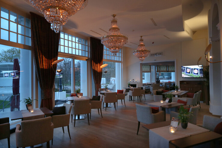 Elegante Hotelbar mit Kronleuchtern, gemütlichen Sitzbereichen und großen Fenstern mit Blick nach draußen.