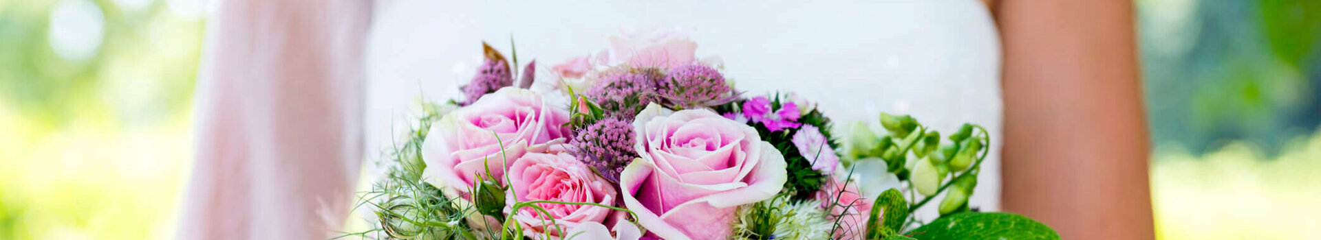 Wedding celebration in the ATLANTIC Hotel Airport Bremen Bride holding a lush bouquet of pink roses with green accents against a blurred green background.