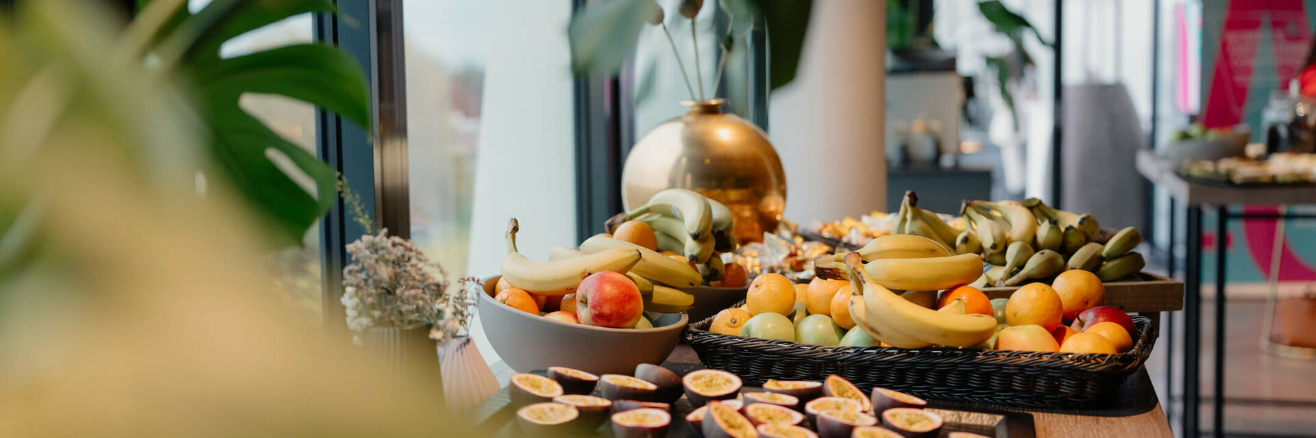 Frühstückstisch im ATLANTIC Hotel Münster mit frischen Früchten wie Bananen, Äpfeln und Passionsfrüchten.