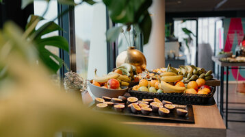Frühstückstisch im ATLANTIC Hotel Münster mit frischen Früchten wie Bananen, Äpfeln und Passionsfrüchten.