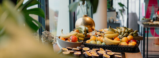 Tagungspauschale Green im ATLANTIC Hotel Münster Frühstückstisch im ATLANTIC Hotel Münster mit frischen Früchten wie Bananen, Äpfeln und Passionsfrüchten.