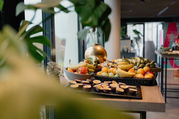 Frühstückstisch im ATLANTIC Hotel Münster mit frischen Früchten wie Bananen, Äpfeln und Passionsfrüchten.