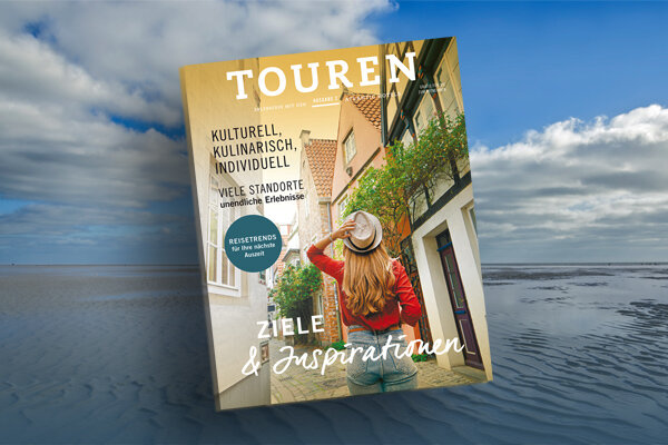 Cover of a travel magazine against a beach background, showing a woman in an alley with a hat and red sweater.