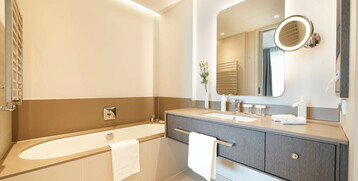 Modern bathroom at the ATLANTIC Grand Hotel Bremen with bathtub, double washbasin and large mirror.