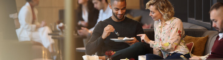 Guests enjoy their break in the Deli Lounge at the ATLANTIC Hotel Heidelberg with a sweet snack.