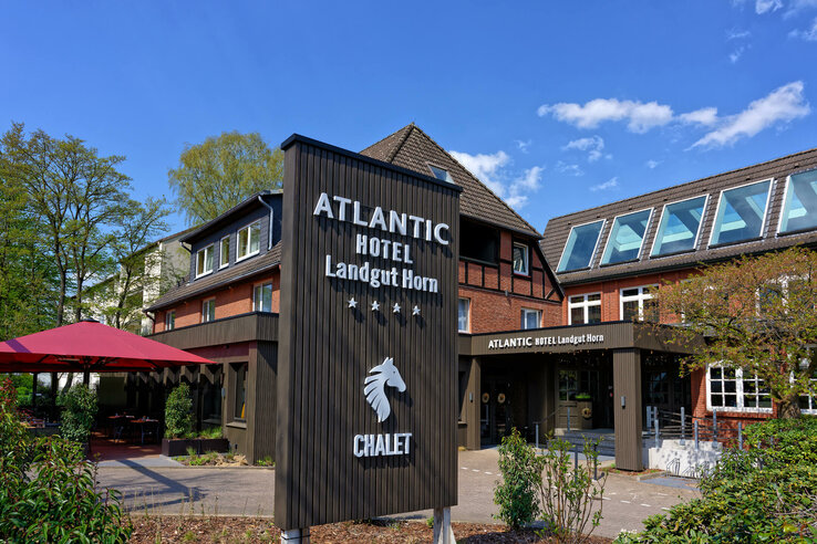 Außenansicht des ATLANTIC Hotel Landgut Horn Bremen mit Schild und Eingangsbereich bei sonnigem Wetter.