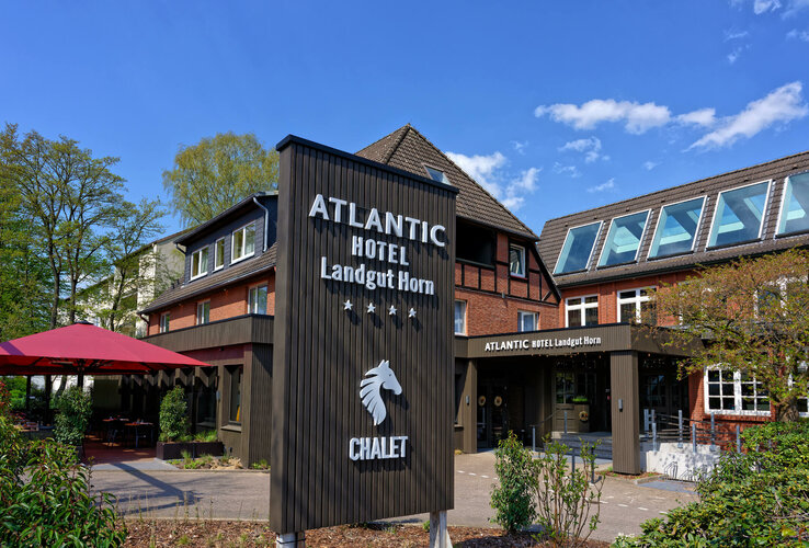 Außenansicht des ATLANTIC Hotel Landgut Horn Bremen mit Schild und Eingangsbereich bei sonnigem Wetter.