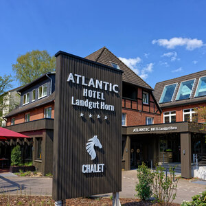 Exterior view of the ATLANTIC Hotel Landgut Horn Bremen with sign and entrance area in sunny weather.