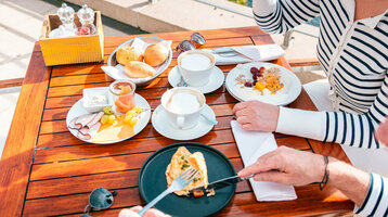 Zwei Personen frühstücken auf der Außenterrasse