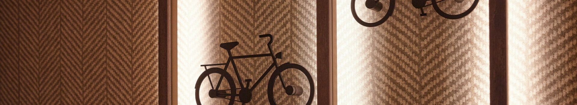 Two stylized bicycles as wall decoration on a patterned background in the ATLANTIC Hotel Münster.