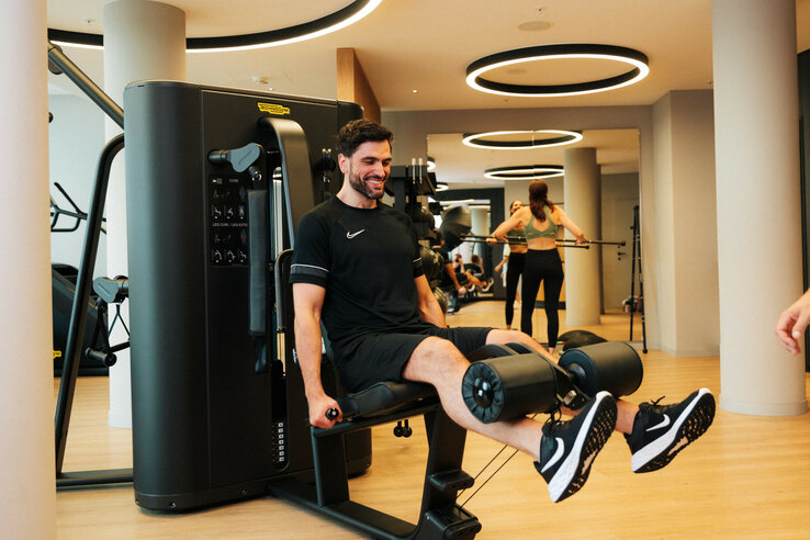 Mann trainiert an Fitnessgerät im modernen Fitnessstudio des ATLANTIC Hotel Heidelberg.