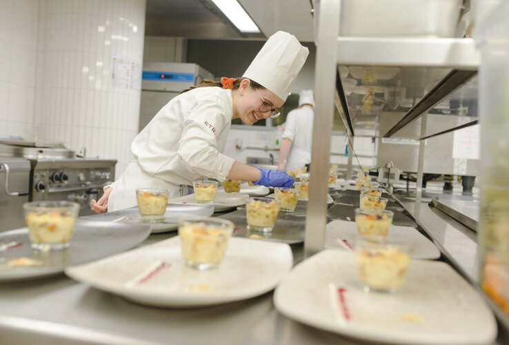 Cook at the ATLANTIC Hotel Sail City decorates dessert glasses in the hotel kitchen.