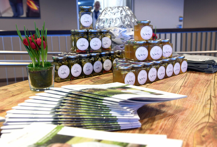 Tisch mit Gläsern regionaler Produkte, Broschüren und roten Tulpen im ATLANTIC Hotel Sail City, Bremerhaven.