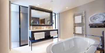Modern bathroom in the ATLANTIC Grand Hotel Bremen with free-standing bathtub, double washbasin and towel rail.