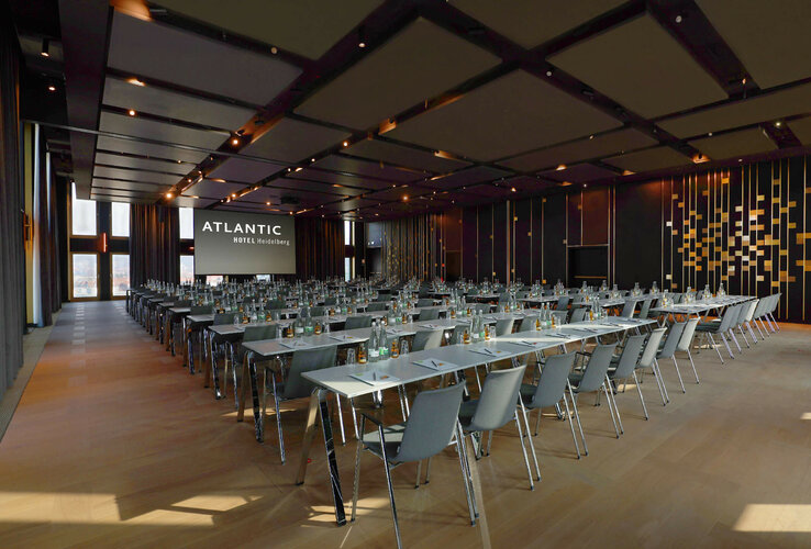 Parlamentarisch bestuhlter Ballsaal im ATLANTIC Hotel Heidelberg mit Blick auf die ausgefahrene Leinwand