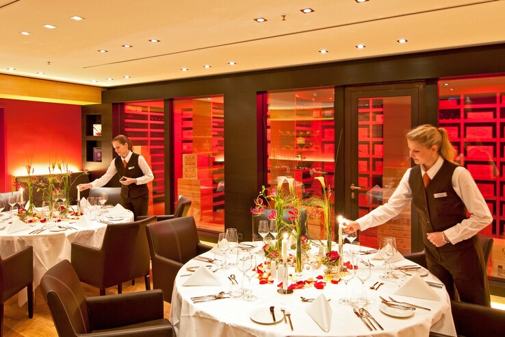 Elegantes Restaurant im ATLANTIC Hotel Kiel mit festlich gedeckten Tischen und Servicemitarbeitern.