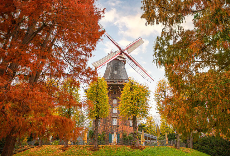 Historic windmill in autumn, surrounded by colorful trees, near the ATLANTIC Grand Hotel Bremen.