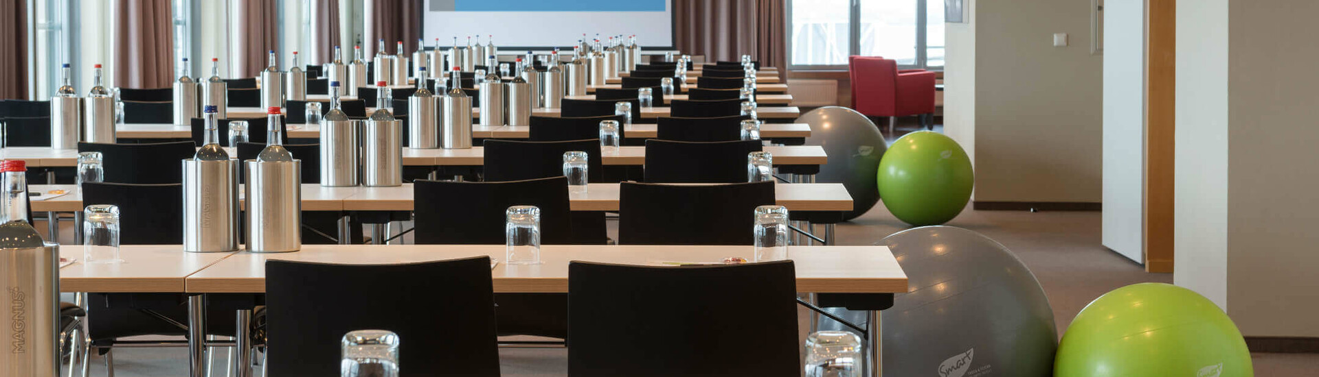 Veranstaltungsraum Junkers und Lilienthal im ATLANTIC Hotel Airport Bremen Konferenzraum im ATLANTIC Hotel Airport Bremen mit Tischen, Stühlen, Wasserflaschen und Gymnastikbällen.