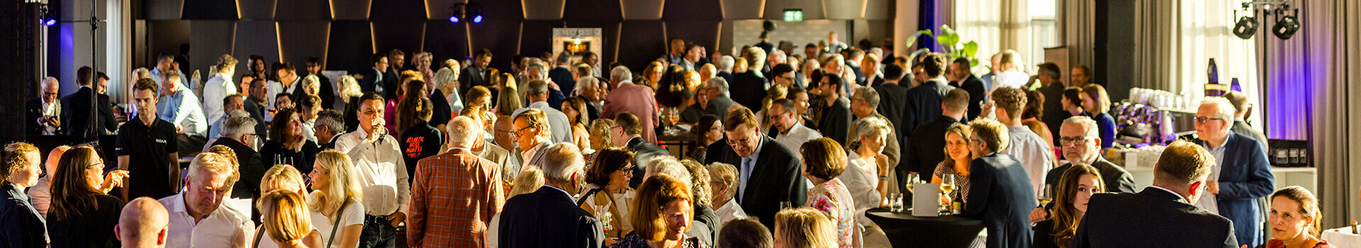 Large crowd at an event at the ATLANTIC Hotel Münster, in an elegantly lit room.