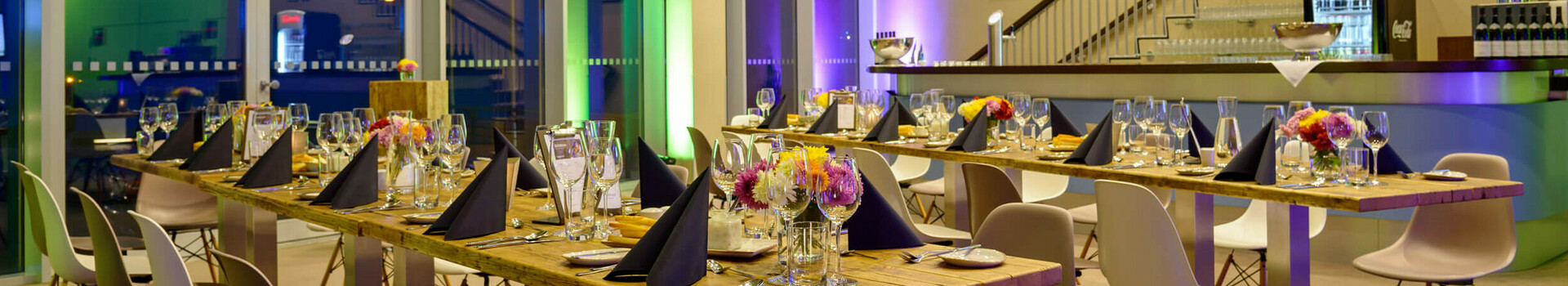 Modernes Restaurant im ATLANTIC Hotel Sail City, elegant gedeckte Tische, große Fenster, stimmungsvolle Beleuchtung.