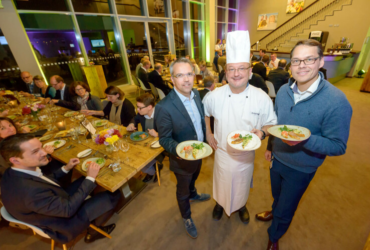 Gruppe bei festlichem Dinner im ATLANTIC Hotel Sail City, Bremerhaven, mit Chefkoch und Speisen.