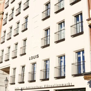 Façade of the LOUIS Hotel in Munich with several windows and a historic neighboring building.
