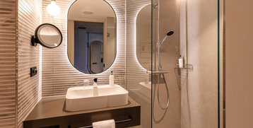 A modern washbasin, rain shower and illuminated mirror.