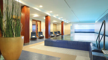 Wellnessbereich mit Schwimmbad im ATLANTIC Grand Hotel Travemünde Heller Innenpoolbereich im ATLANTIC Grand Hotel Travemünde mit Liegestühlen und Pflanzen.