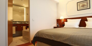 Bedroom of the Gorch Fock Suite with an open door to the bathroom in the ATLANTIC Hotel Wilhelmshaven 